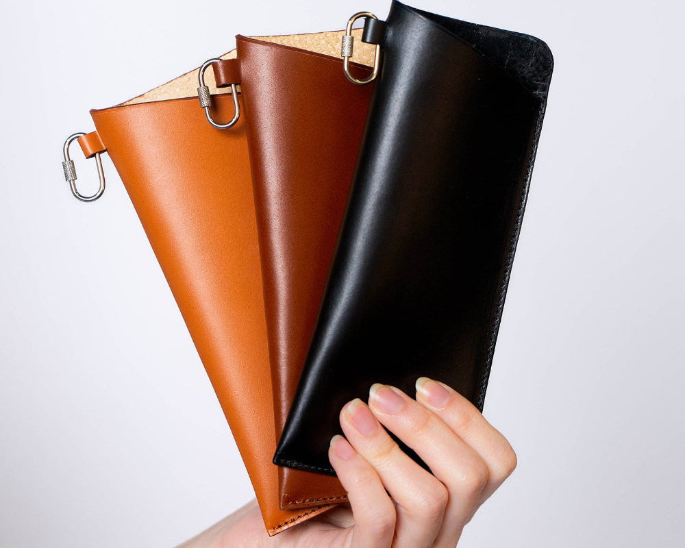 Minimal leather glasses case — ÉTUI LUNETTES by atelier &LAB, black, brown and cognac upcycled full-grain calf leather eyewear cases held in hand, Paris design studio.