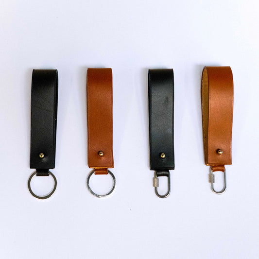 Minimal leather key holder — MODULE by atelier &LAB, black and cognac upcycled full-grain calf leather key holders shown in front view with key ring and carabiner clip, Paris design studio.