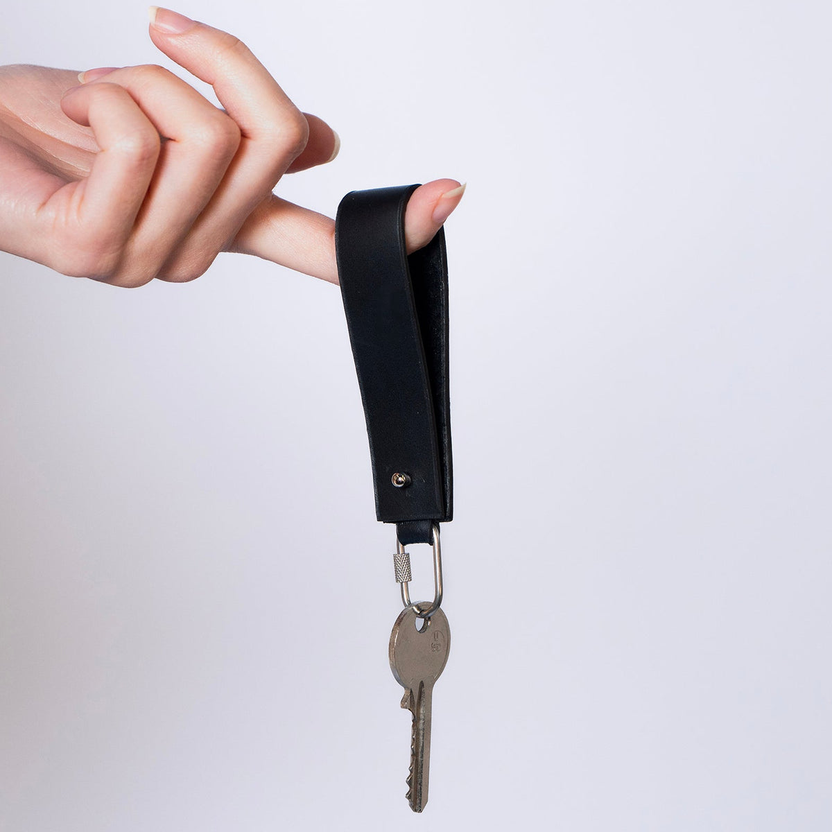 Minimal leather key holder — MODULE by atelier &LAB, black upcycled full-grain calf leather key holder held in hand with keys, Paris design studio.
