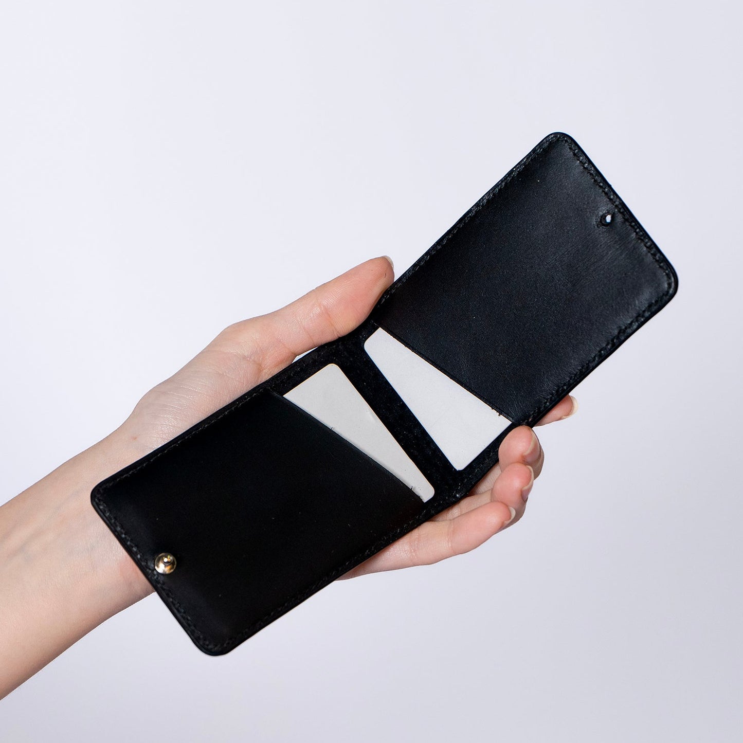 MagSafe compatible leather smartphone card holder — MODULE Pliable by atelier &LAB, black upcycled full-grain calf leather shown open in hand, Paris design studio.