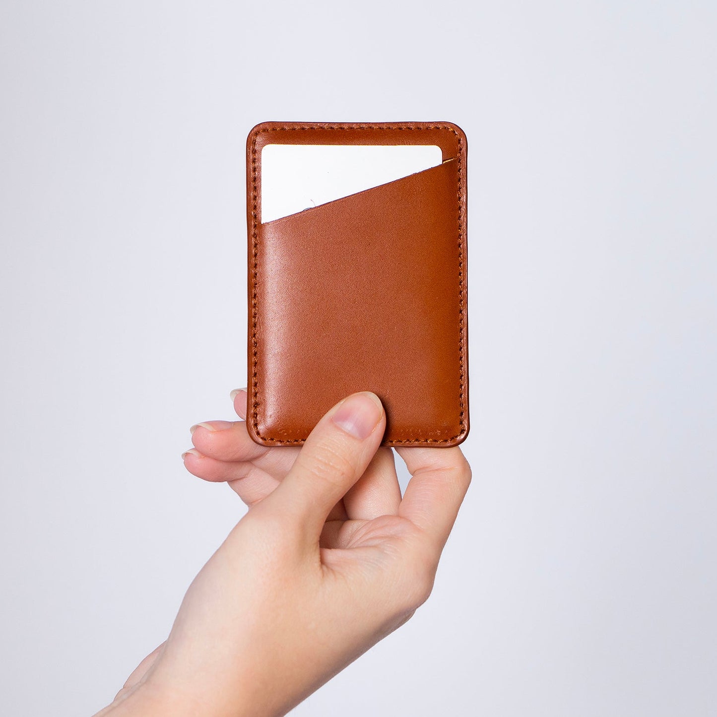 MagSafe compatible leather smartphone card holder — MODULE Simple by atelier &LAB, cognac upcycled full-grain calf leather held in hand, Paris design studio.