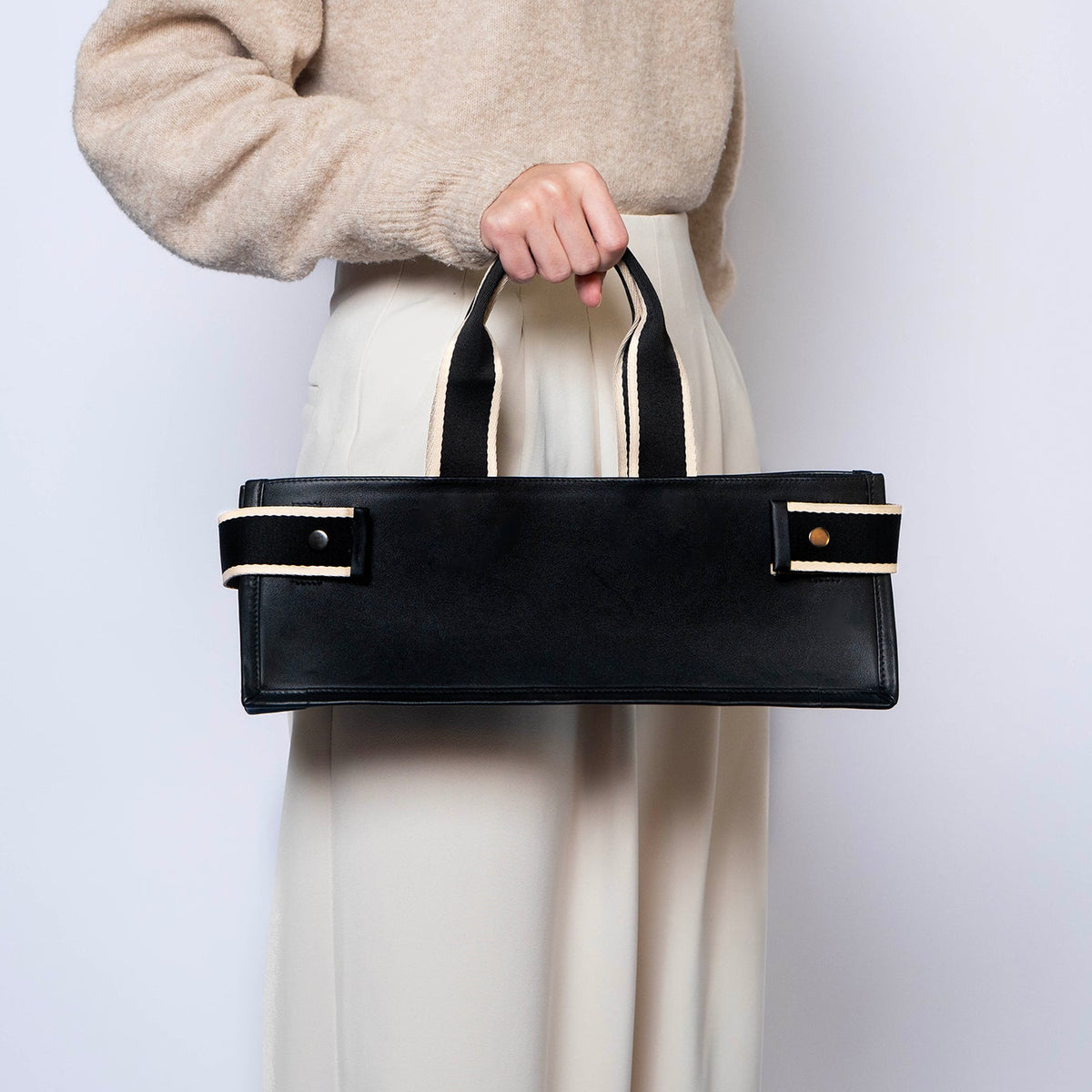 Minimal structured leather tote bag — NUMÉRO 02 PLAT by atelier &LAB, black upcycled full-grain calf leather, front view handheld showing a clean flat structured shape for everyday use.