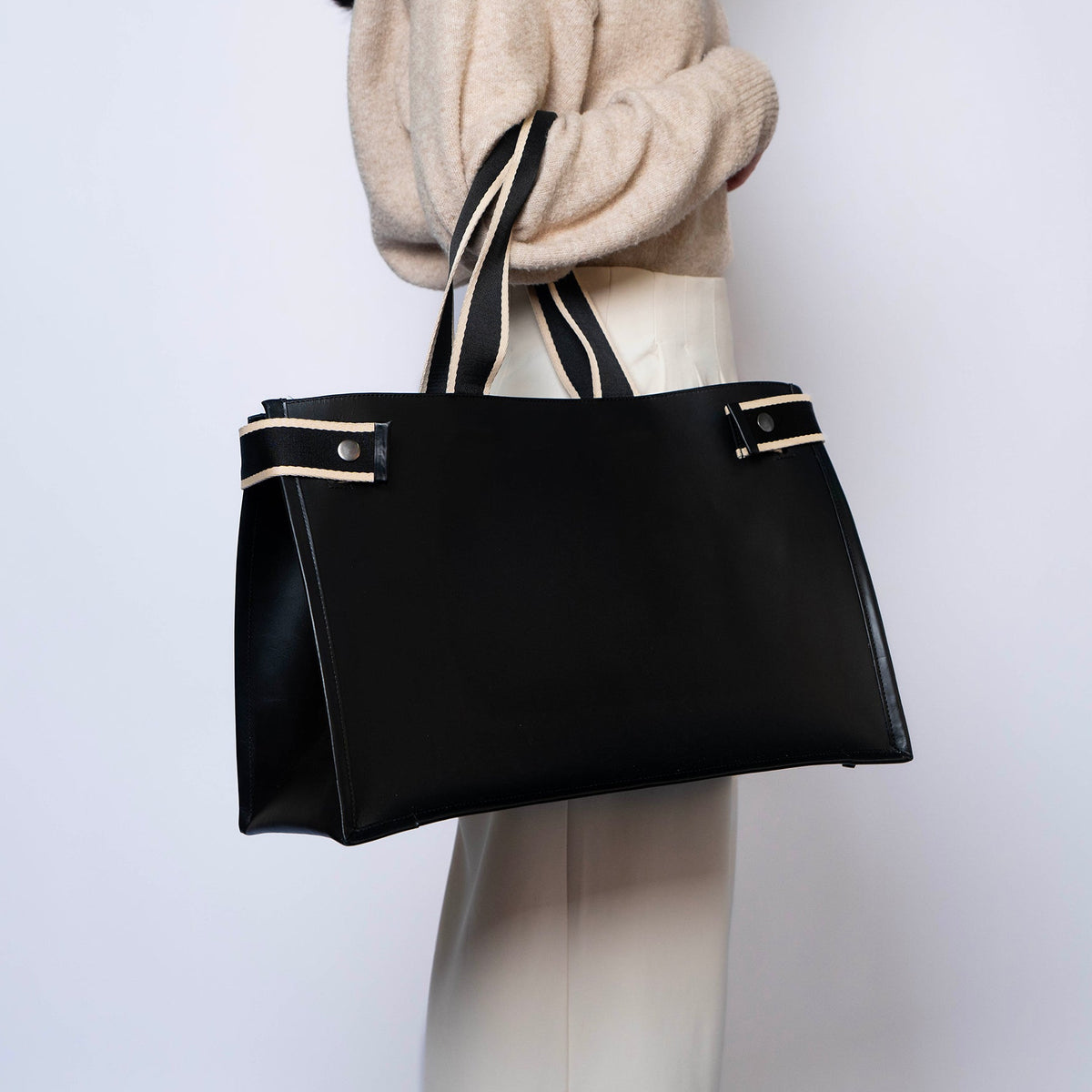 Minimal structured leather tote bag — NUMÉRO 02 by atelier &LAB, black upcycled full-grain calf leather, front view carried on arm showing a clean, structured silhouette designed for everyday use.