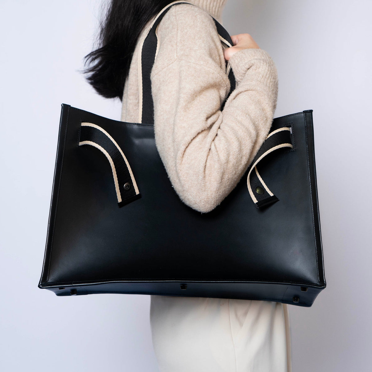 Minimal structured leather tote bag — NUMÉRO 02 by atelier &LAB, black upcycled full-grain calf leather, side view worn on shoulder showing a clean, structured shape for everyday use.
