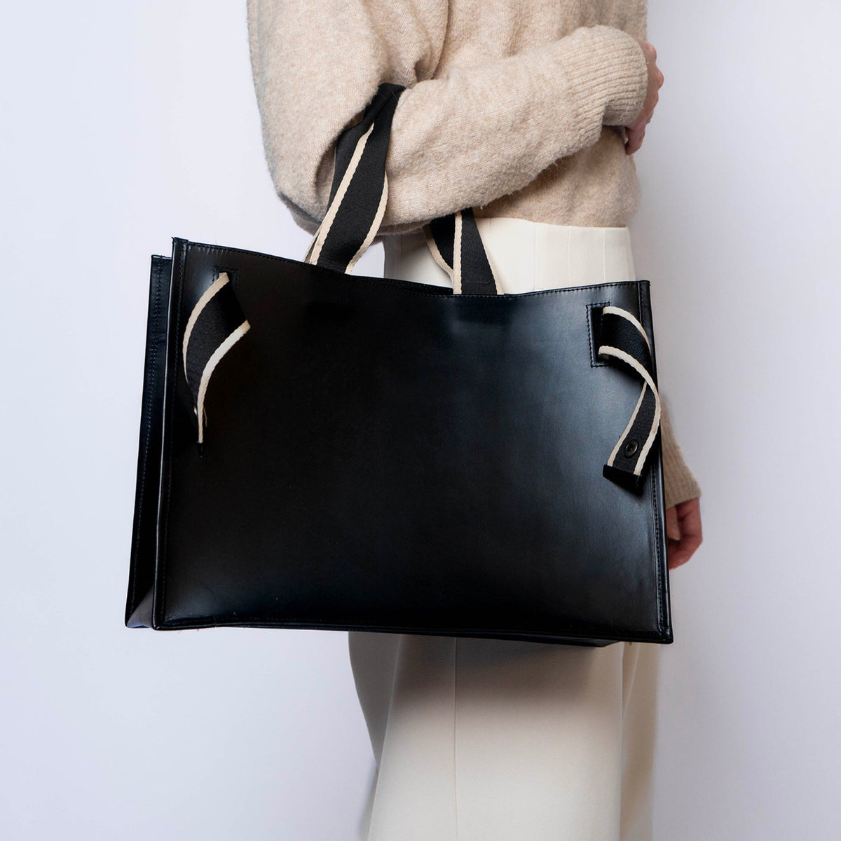Minimal structured leather tote bag — NUMÉRO 02 by atelier &LAB, black upcycled full-grain calf leather, side view worn on shoulder showing a clean structured shape for everyday use.