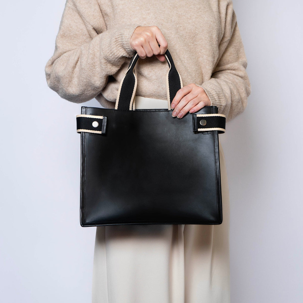 Minimal structured leather tote bag — NUMÉRO 02 by atelier &LAB, black upcycled full-grain calf leather, front view handheld showing a clean structured shape for everyday use.