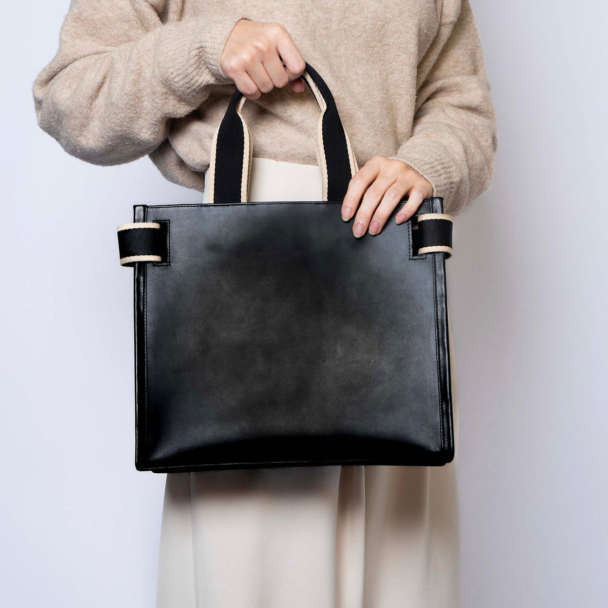 Minimal structured leather tote bag — NUMÉRO 02 by atelier &LAB, black upcycled full-grain calf leather, rear view handheld showing a clean structured shape for everyday use.