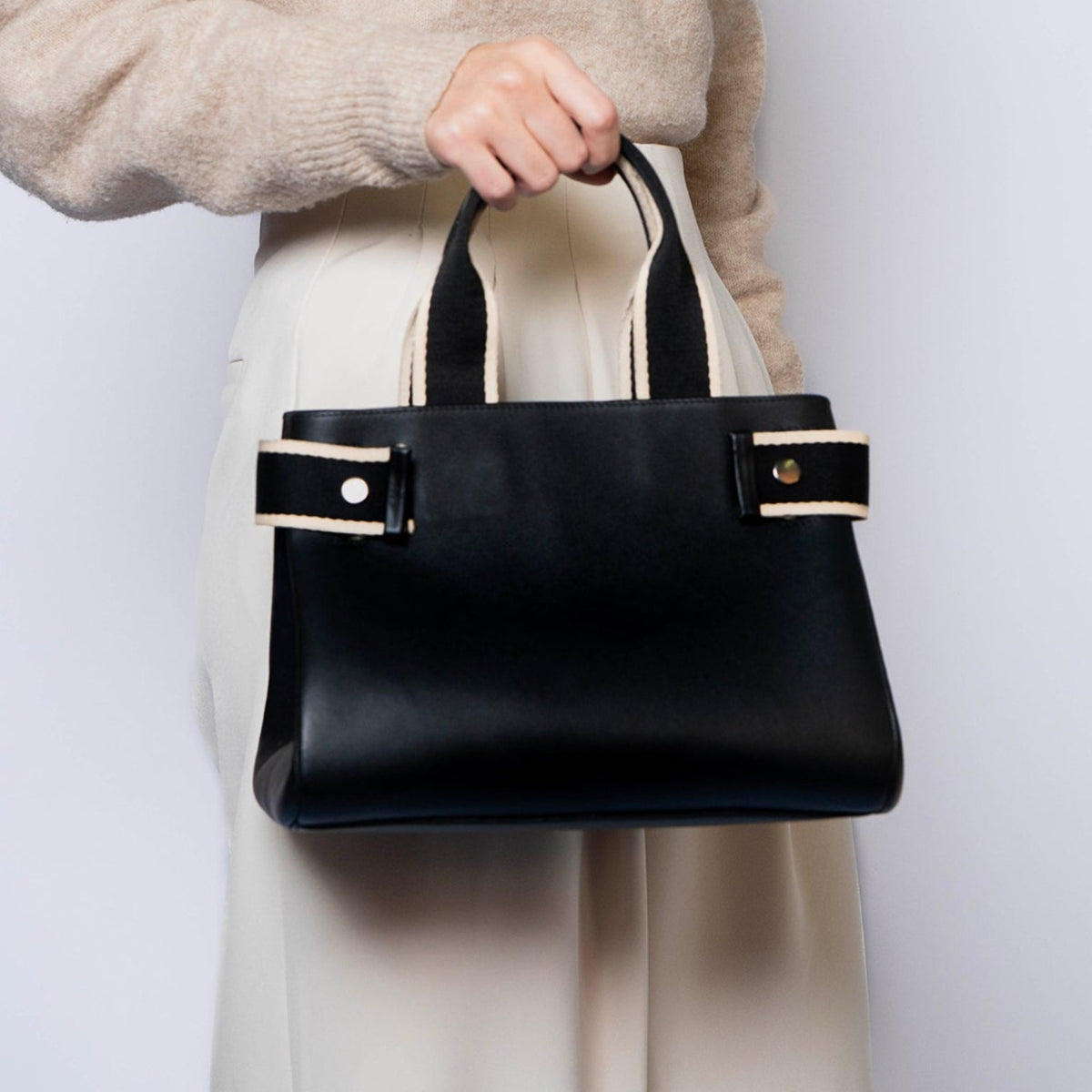 Structured leather handbag — NUMÉRO 04 M by atelier &LAB, handheld frontal view, black upcycled full-grain calf leather, compact structured silhouette, designed near Paris