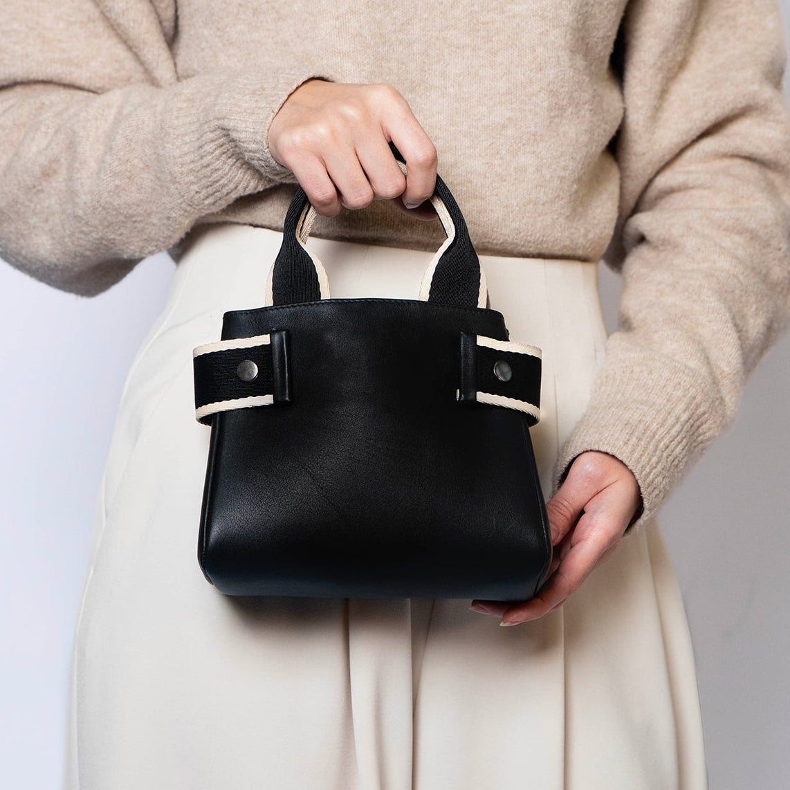 Mini leather handbag in black — NUMÉRO 04 by atelier &LAB, handheld front view, compact shape