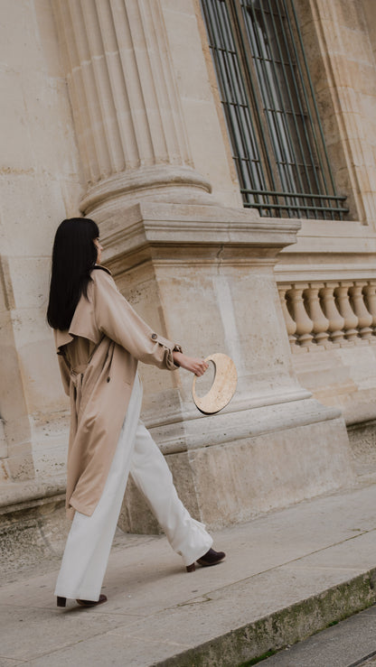ARCHIVE 01 by atelier &LAB — circular Mineral Composite (stone-based material) bag with integrated mineral handle and Premium beige leather insert, worn in an Editorial Architectural setting at the Louvre, Paris.