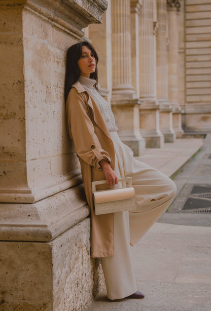 ARCHIVE 02 by atelier &LAB — rectangular Mineral Composite (stone-based material) bag with integrated Mineral handle and Premium beige leather insert, carried in a Minimalist Brutalist Architectural setting at the Louvre, Paris.