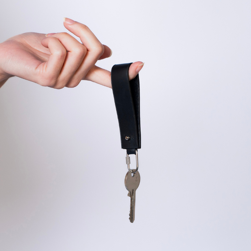 Leather key holder — atelier &LAB, black minimal keychain carried by hand