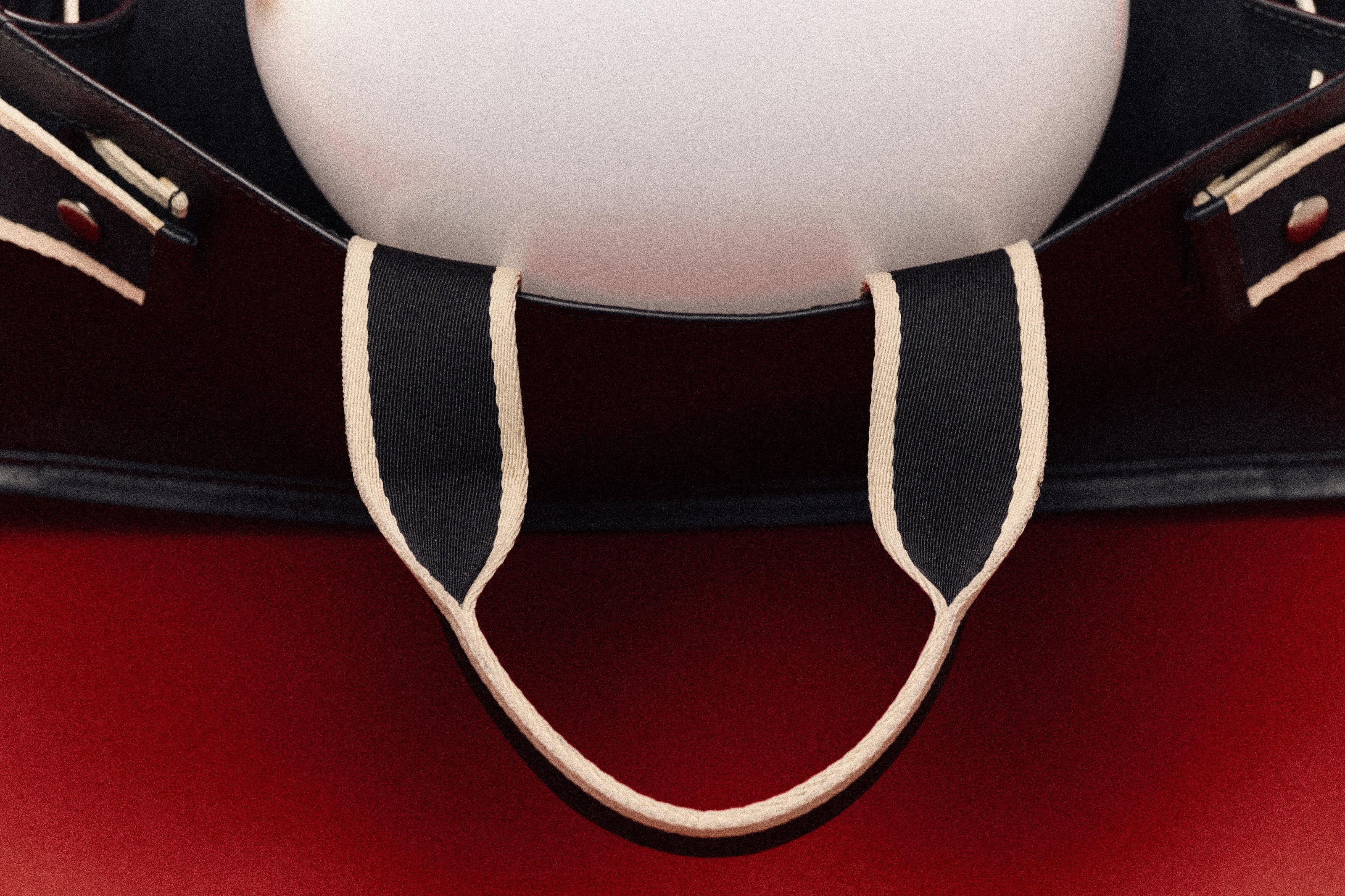 Graphic handle detail of structured leather tote bag — NUMÉRO 01 by atelier &LAB, photographed by Louis Vizet on deep red background
