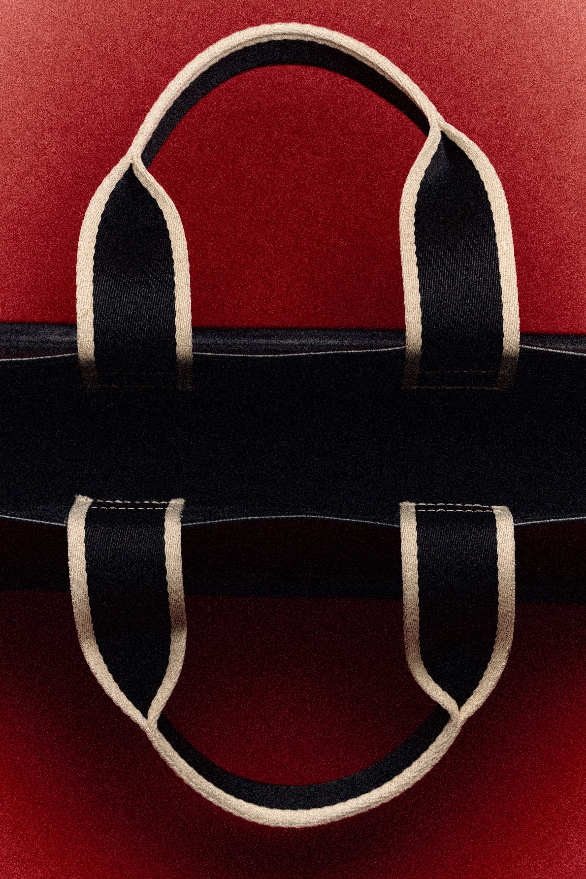 Symmetrical handle detail of structured leather tote bag — NUMÉRO 02 by atelier &LAB, photographed by Louis Vizet on deep red background