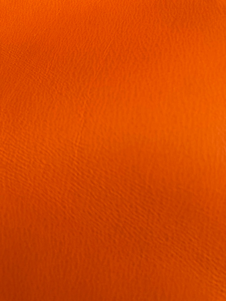 Close-up detail of atelier &LAB orange upcycled full-grain leather, highlighting refined natural grain and Premium Texture.