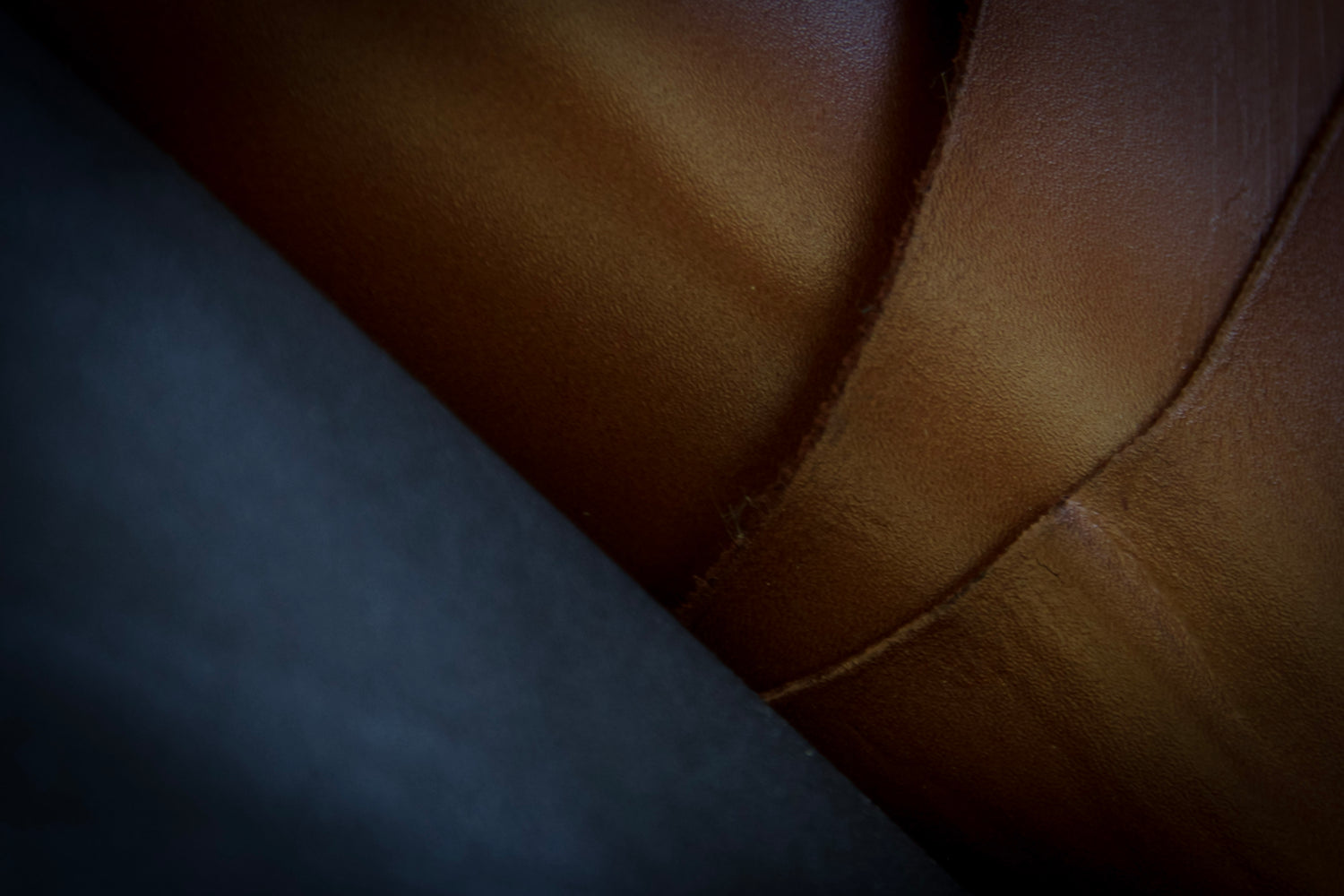 Close-up of layered leather surfaces showing natural texture and seam detail during a material study at the atelier &LAB studio.