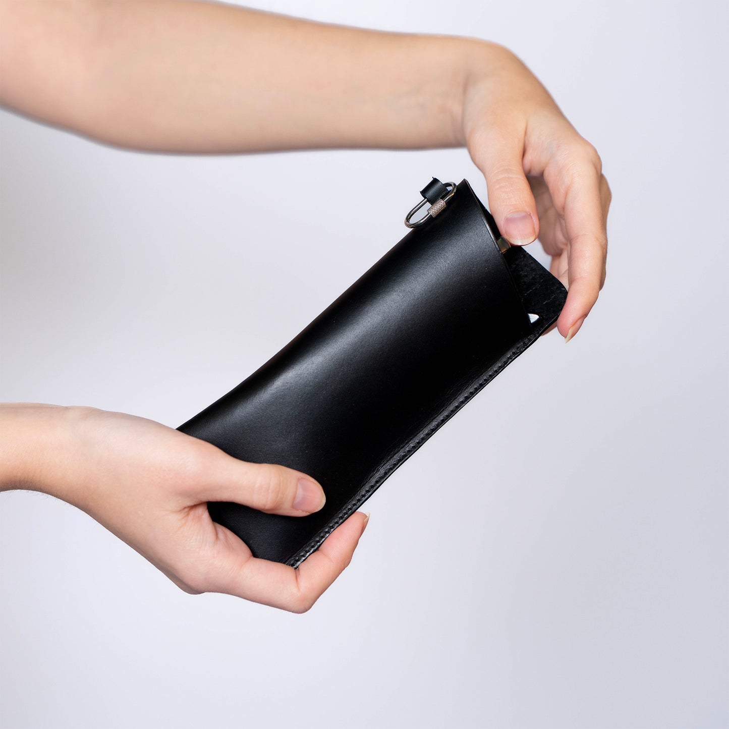 Minimal leather glasses case — ÉTUI LUNETTES by atelier &LAB, black upcycled full-grain calf leather eyewear case held in hand, side view, Paris design studio.