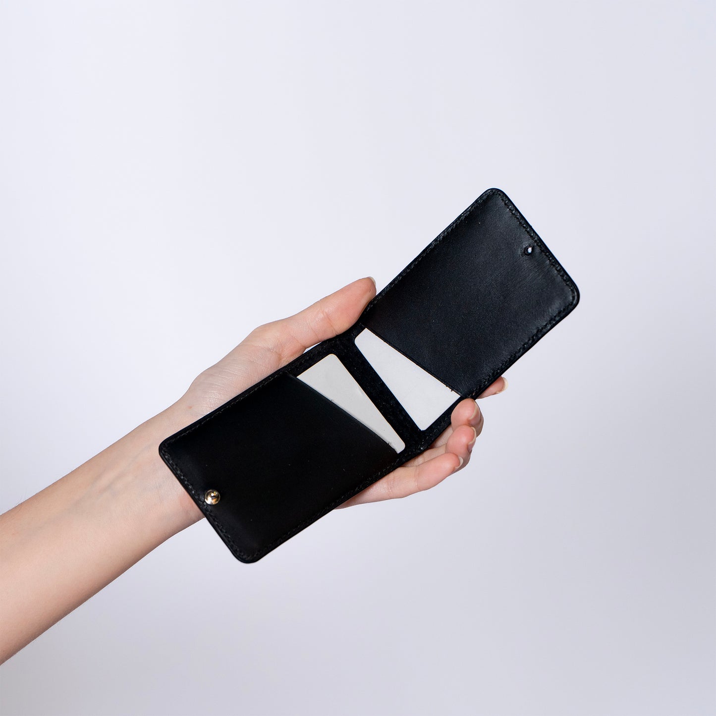 MODULE card holder double by atelier &LAB — hand-held front view revealing a compact, structured leather volume in black, premium upcycled full-grain calf leather, Paris.
