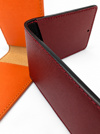 Close-up of two open MODULE Pliable card holders by atelier &LAB in Bordeaux and orange upcycled full-grain calf leather, highlighting the leather grain, hand stitching, black edge finishing and contrasting suede linings. Designed and made near Paris.