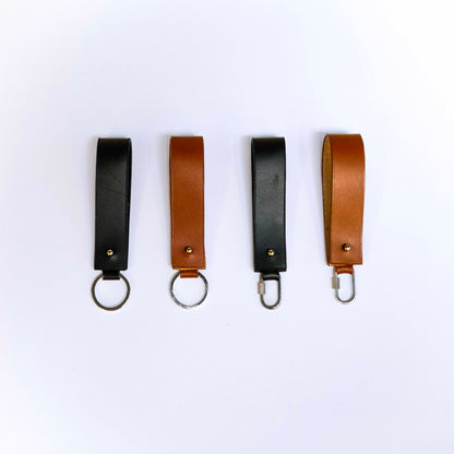 Minimal leather key holder — MODULE by atelier &LAB, black and cognac upcycled full-grain calf leather key holders shown in front view with key ring and carabiner clip, Paris design studio.