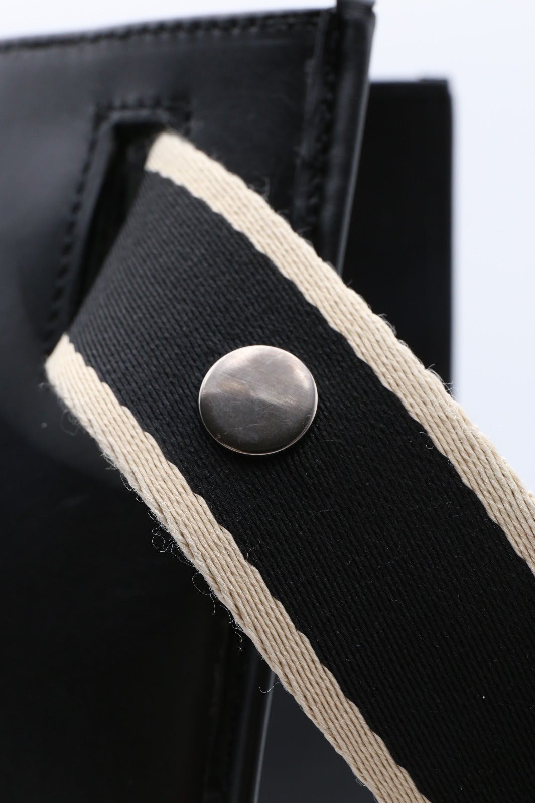 Structured leather tote bag — NUMÉRO 00 MAXI by atelier &LAB, detail view showing handle attachment and metal rivet on black upcycled full-grain calf leather