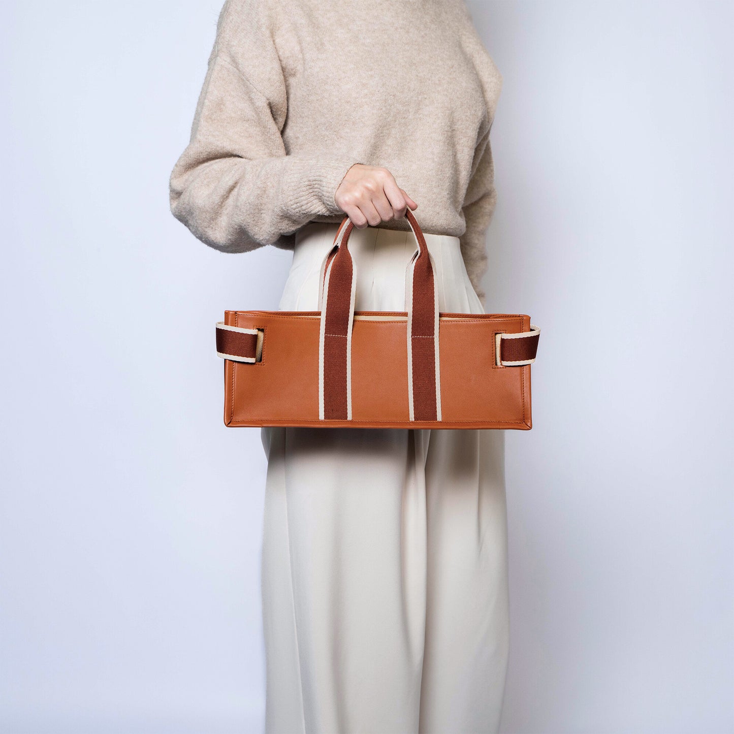 Structured leather tote bag — NUMÉRO 01 FLAT by atelier &LAB, handheld rear view showing flat structured silhouette in cognac upcycled full-grain calf leather