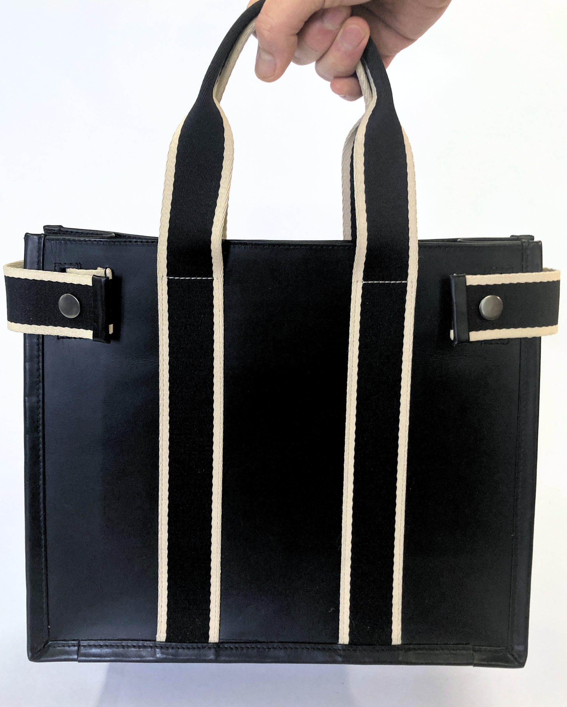 Structured leather tote bag — NUMÉRO 01 S prototype by atelier &LAB, carried by hand showing scale and structured silhouette