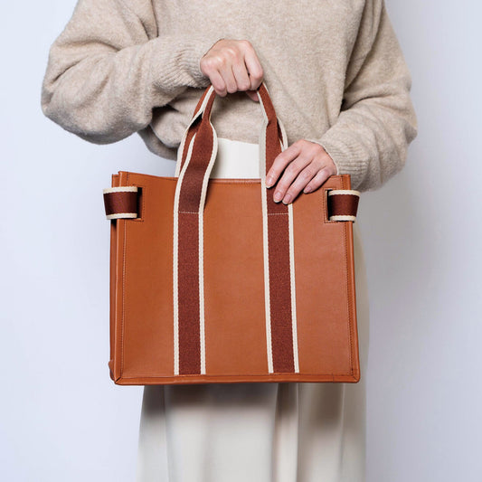 Structured leather tote bag — NUMÉRO 01 S by atelier &LAB, carried in hand rear view showing compact structured shape in cognac calf leather