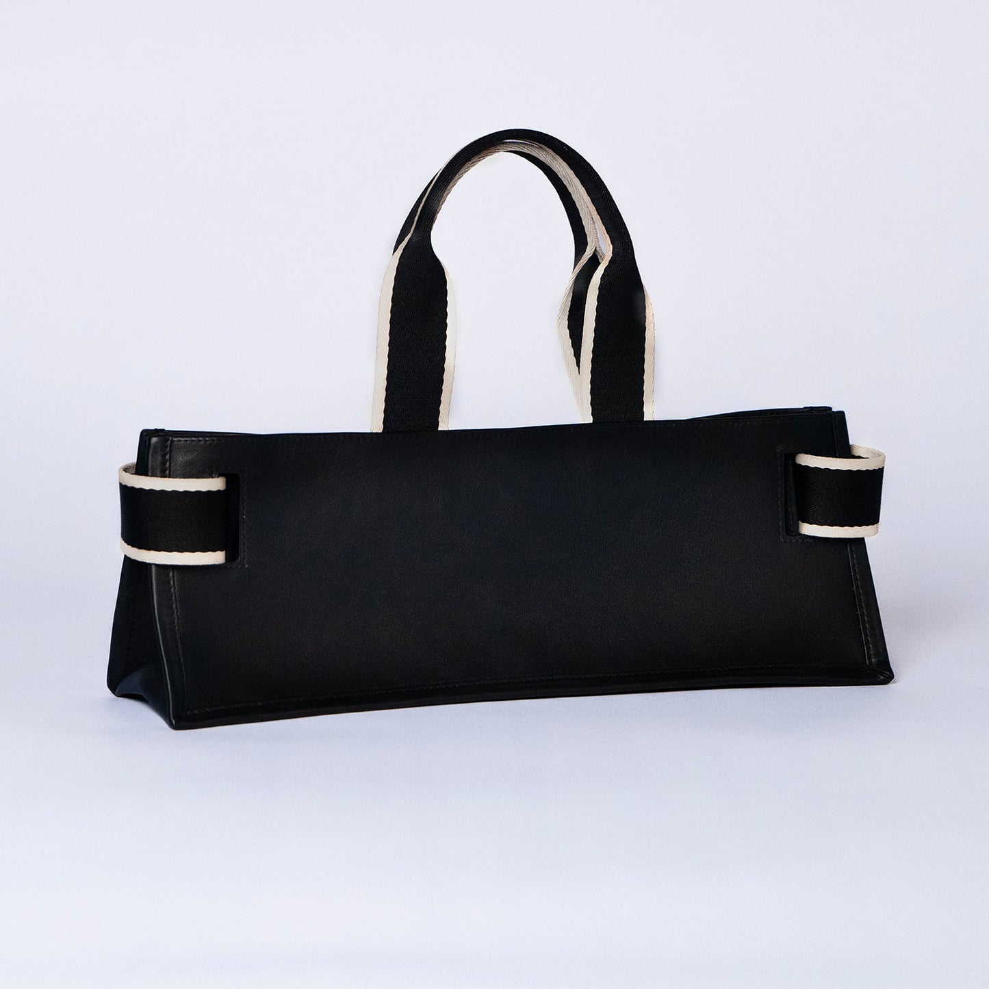 Minimal structured leather tote bag — NUMÉRO 02 PLAT by atelier &LAB, black upcycled full-grain calf leather, rear three-quarter view showing a clean flat structured silhouette.