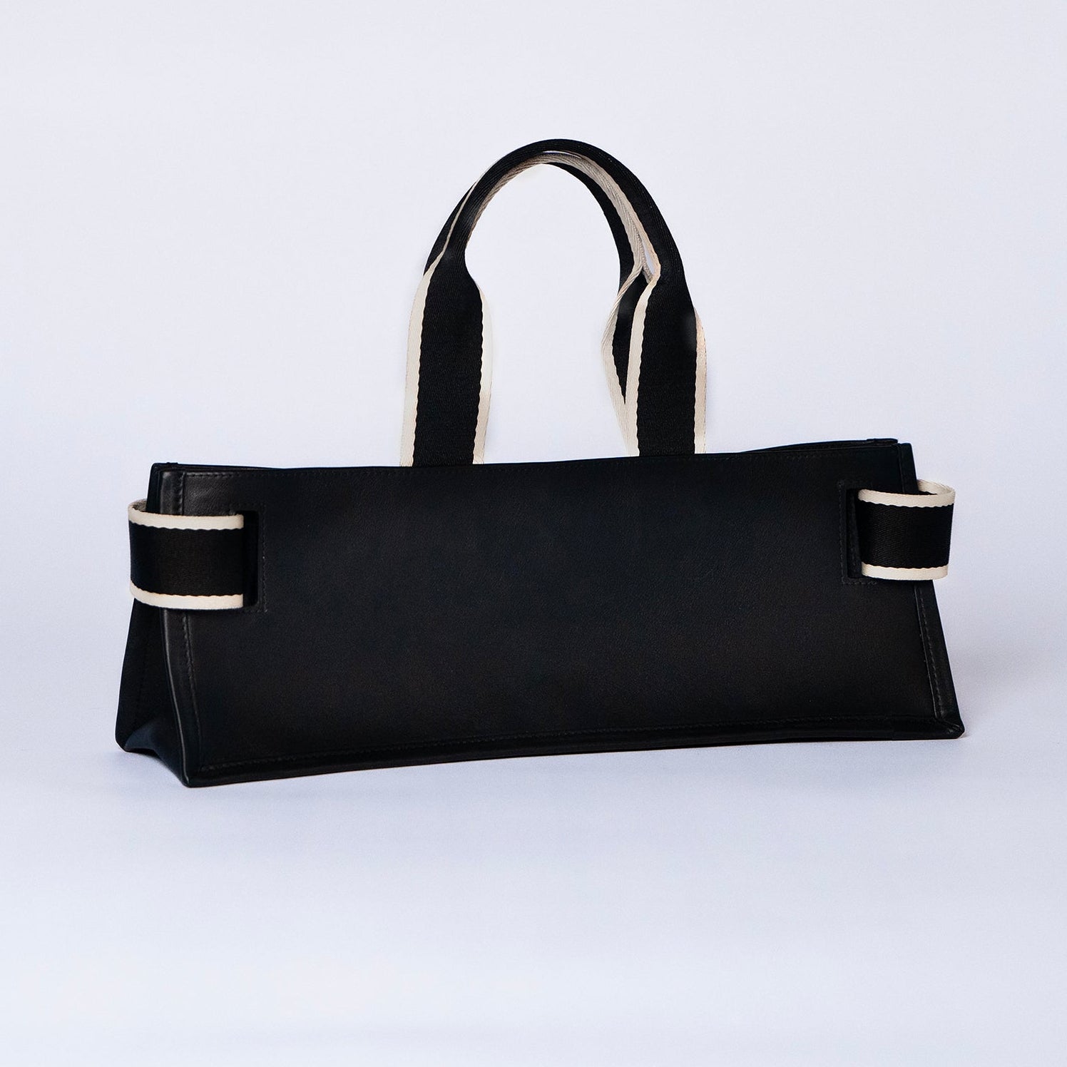 Minimal structured leather tote bag — NUMÉRO 02 PLAT by atelier &LAB, black upcycled full-grain calf leather, rear three-quarter view showing a clean flat structured silhouette.