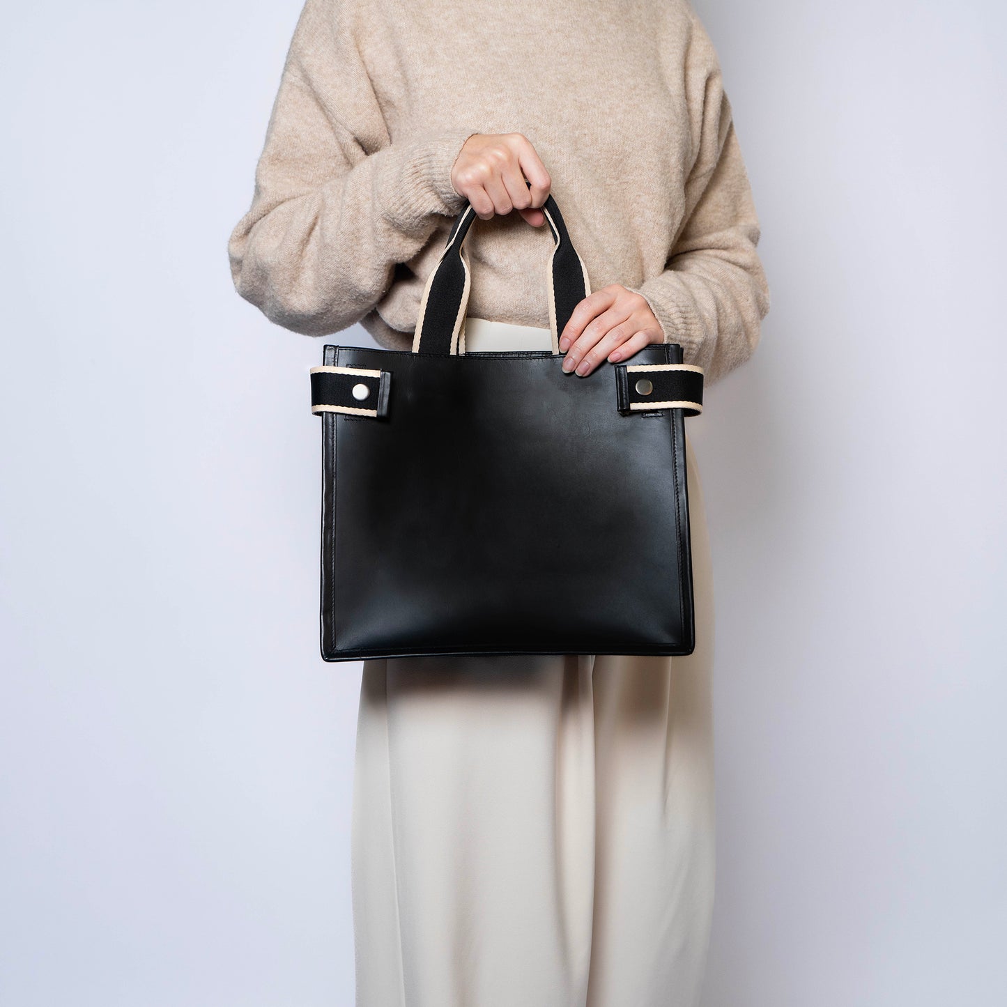 Minimal structured leather tote bag — NUMÉRO 02 by atelier &LAB, black upcycled full-grain calf leather, front view handheld showing a clean structured shape for everyday use.