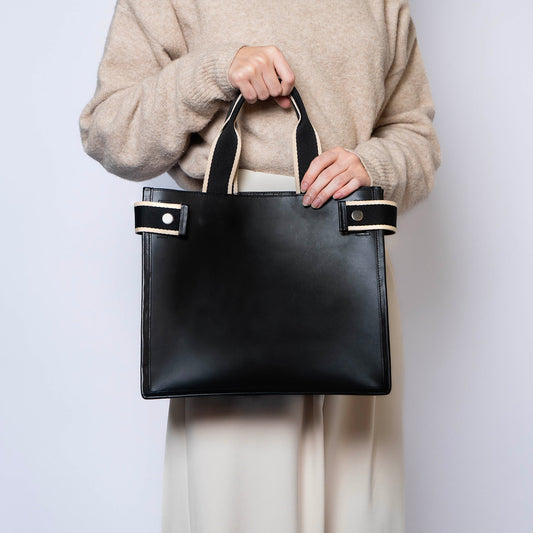 Minimal structured leather tote bag — NUMÉRO 02 by atelier &LAB, black upcycled full-grain calf leather, front view handheld showing a clean structured shape for everyday use.