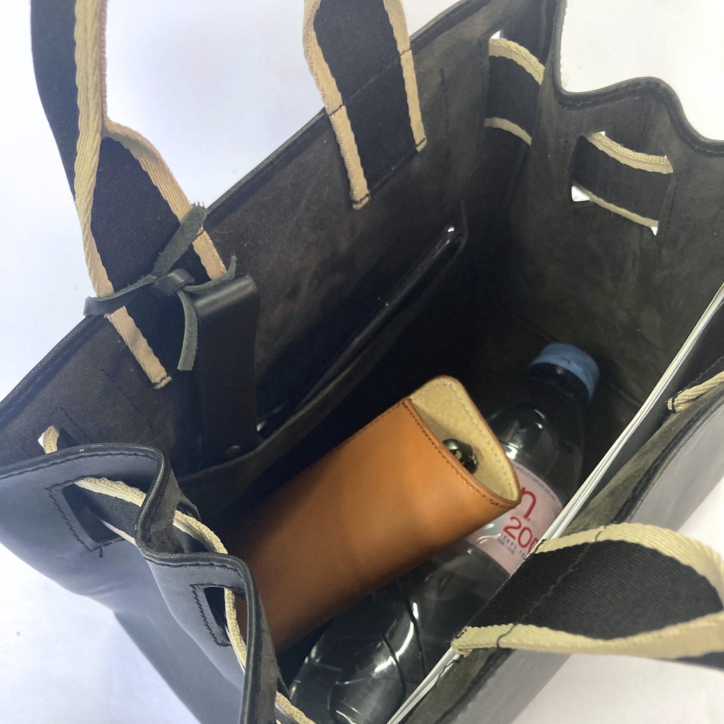 Structured leather handbag — NUMÉRO 04 M prototype by atelier &LAB, interior view showing storage capacity with essentials including bottle and small items