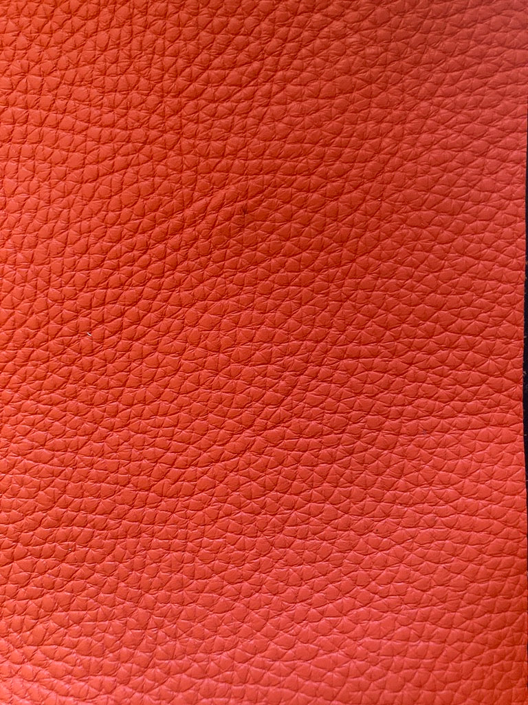 Close-up of red full grained up cycled leather by atelier &LAB, revealing refined texture and natural grain detail.