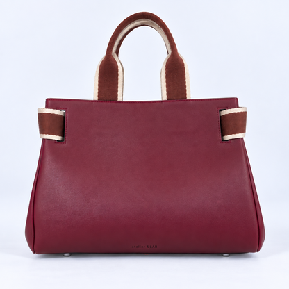 Front view of the NO04 M handbag in Bordeaux upcycled calf leather by Hiroki AMANO — atelier &LAB, featuring contrasting rust and ecru woven handles, softly structured sides and a discreet embossed logo. Designed and made near Paris.
