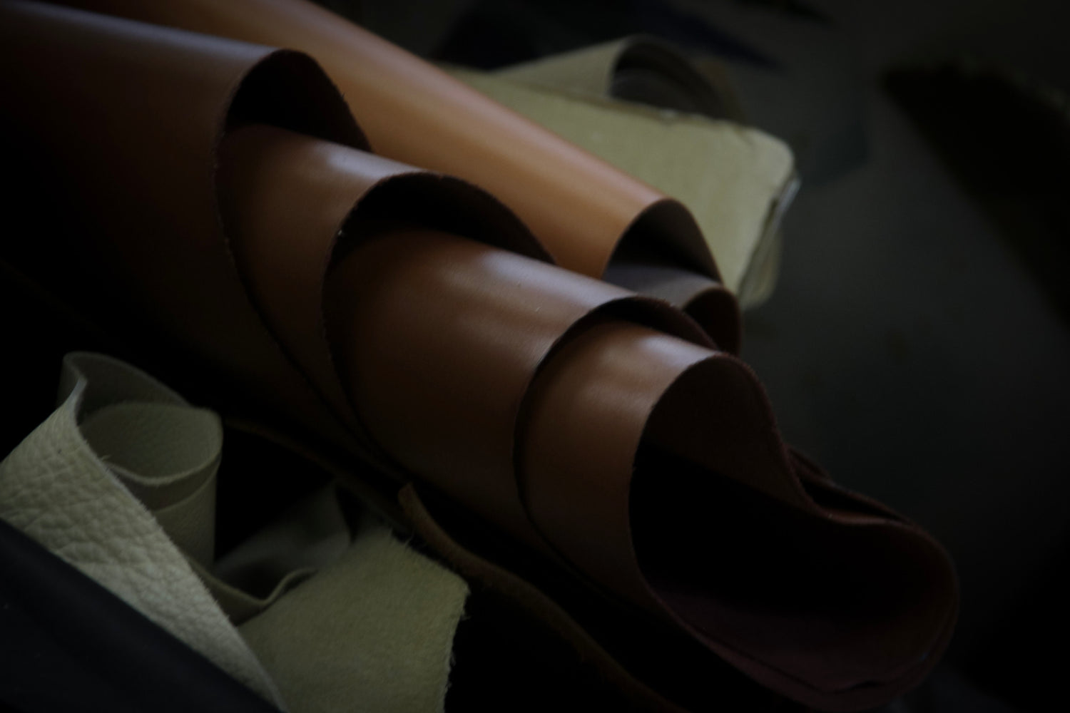 Close-up of layered leather sheets forming curved volumes during a material study at the atelier &LAB studio.